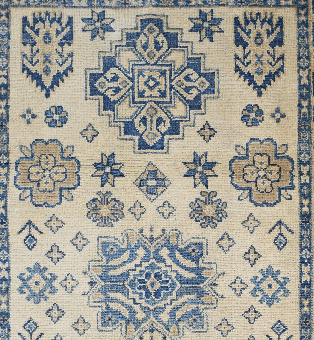 Hand-knotted Afghan Kazakh rug featuring blue and beige geometric medallions and tribal motifs on a wool pile.