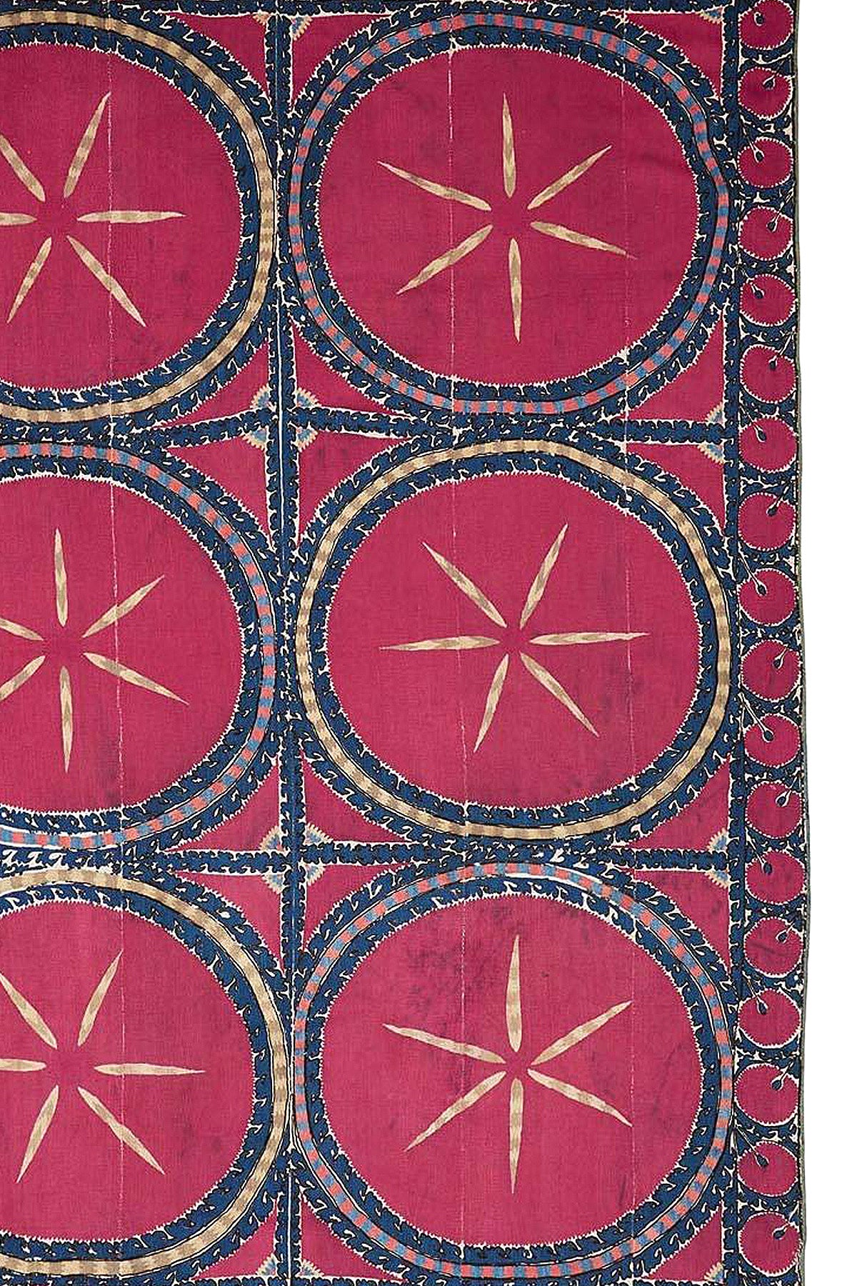 An antique silk Uzbek suzani featuring large circular celestial motifs in red and blue.