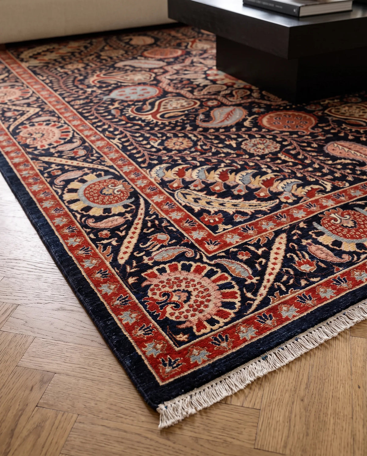 Hand-knotted Afghan Balkh rug with a navy blue field, intricate floral patterns in red and cream, and a short knotted fringe.