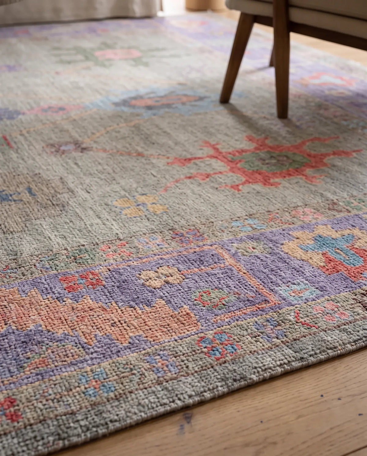 Hand-knotted Afghan wool rug with a muted grey base and colourful floral Oushak-style motifs in a low-pile texture.