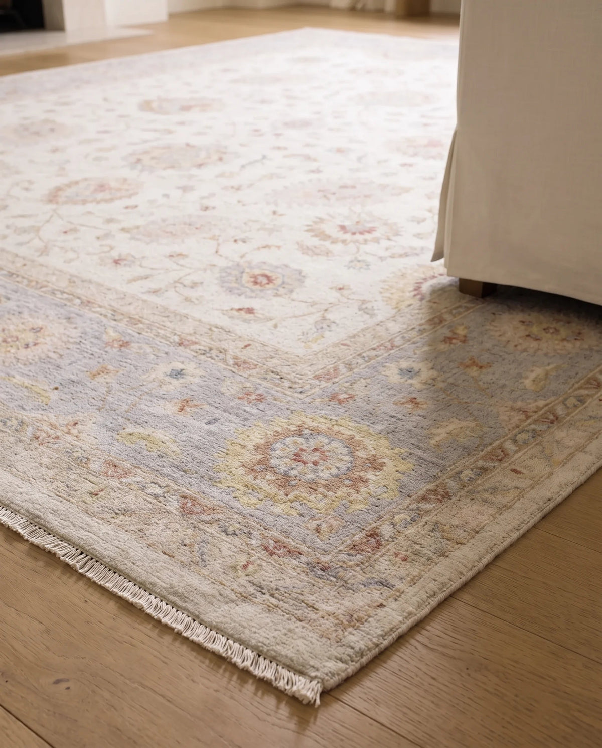 Hand-knotted Afghan Chobi rug with a cream base, floral motifs in soft blue and terracotta, and a short knotted fringe.