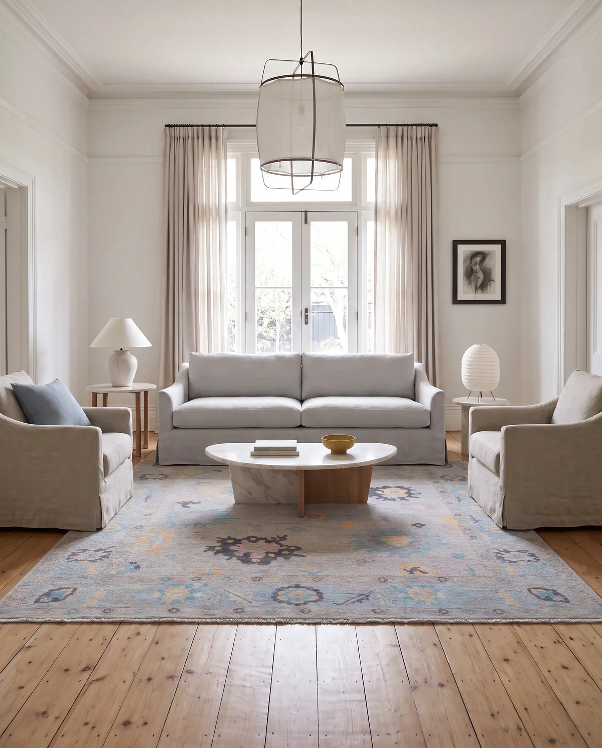 Hand-knotted Afghan wool rug with a muted floral Oushak pattern in blue and gold, styled in a bright, modern living room.