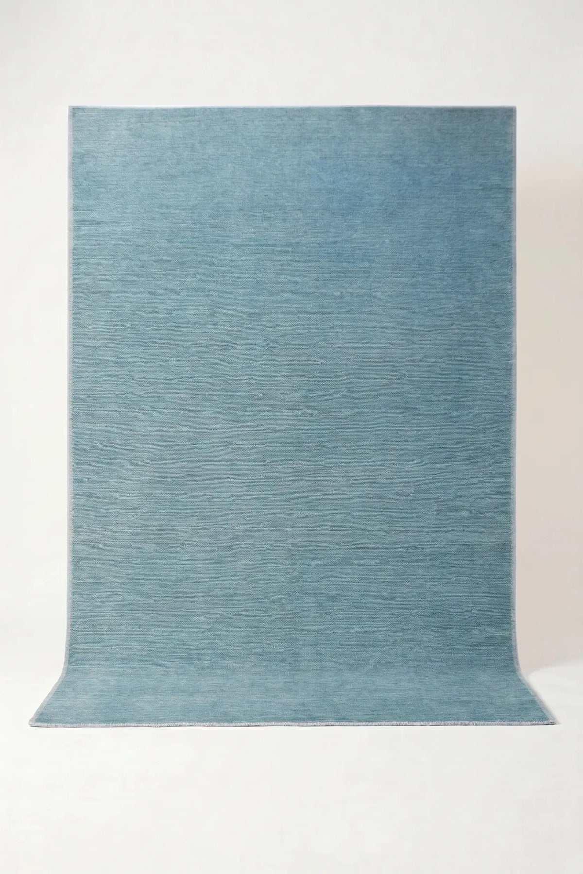 Hand-knotted Afghan wool rug in a solid, lustrous blue with subtle tonal variations and a clean, contemporary finish.