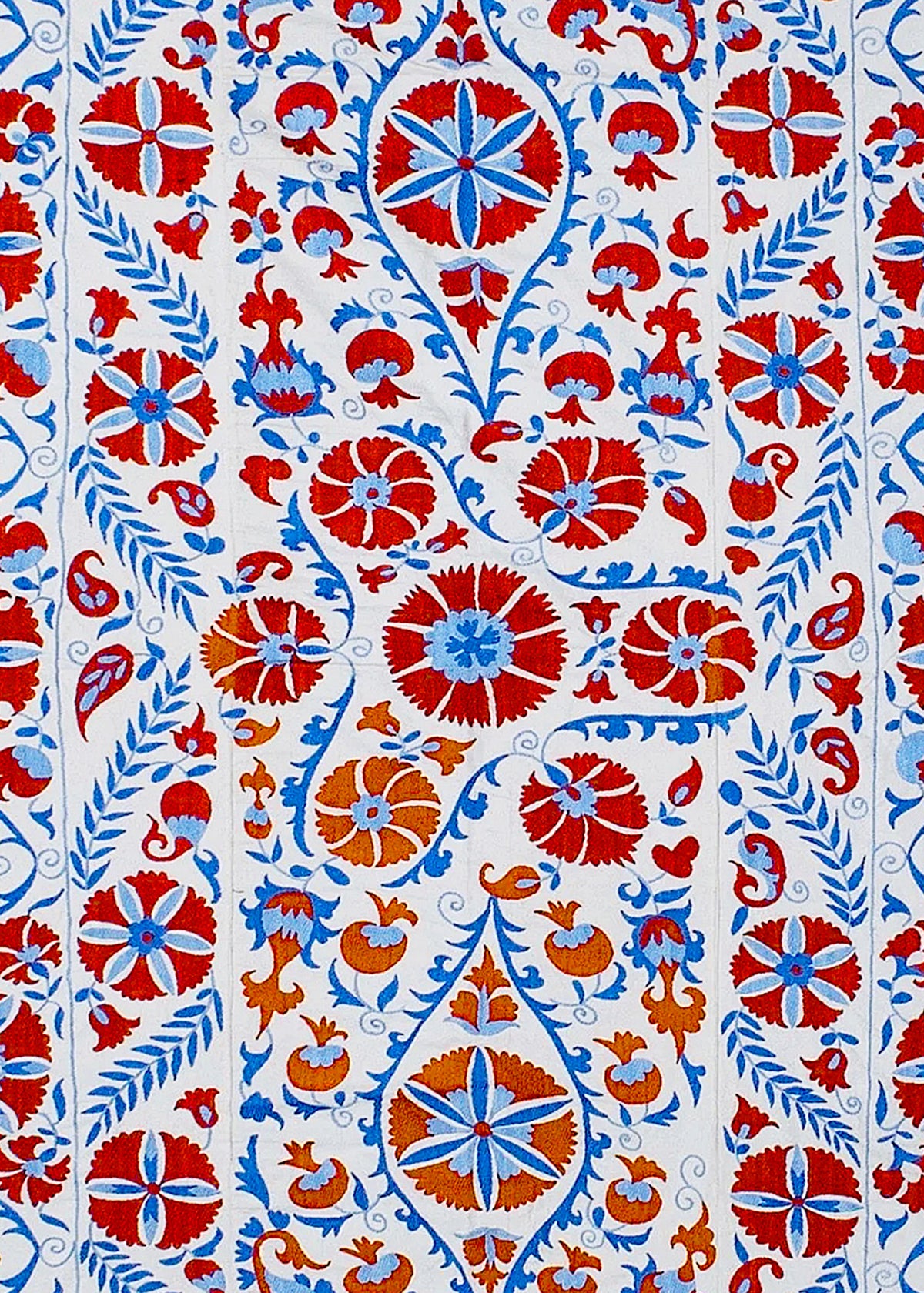 Hand-embroidered Uzbek Suzani textile featuring red, blue, and orange floral motifs on a white cotton background.