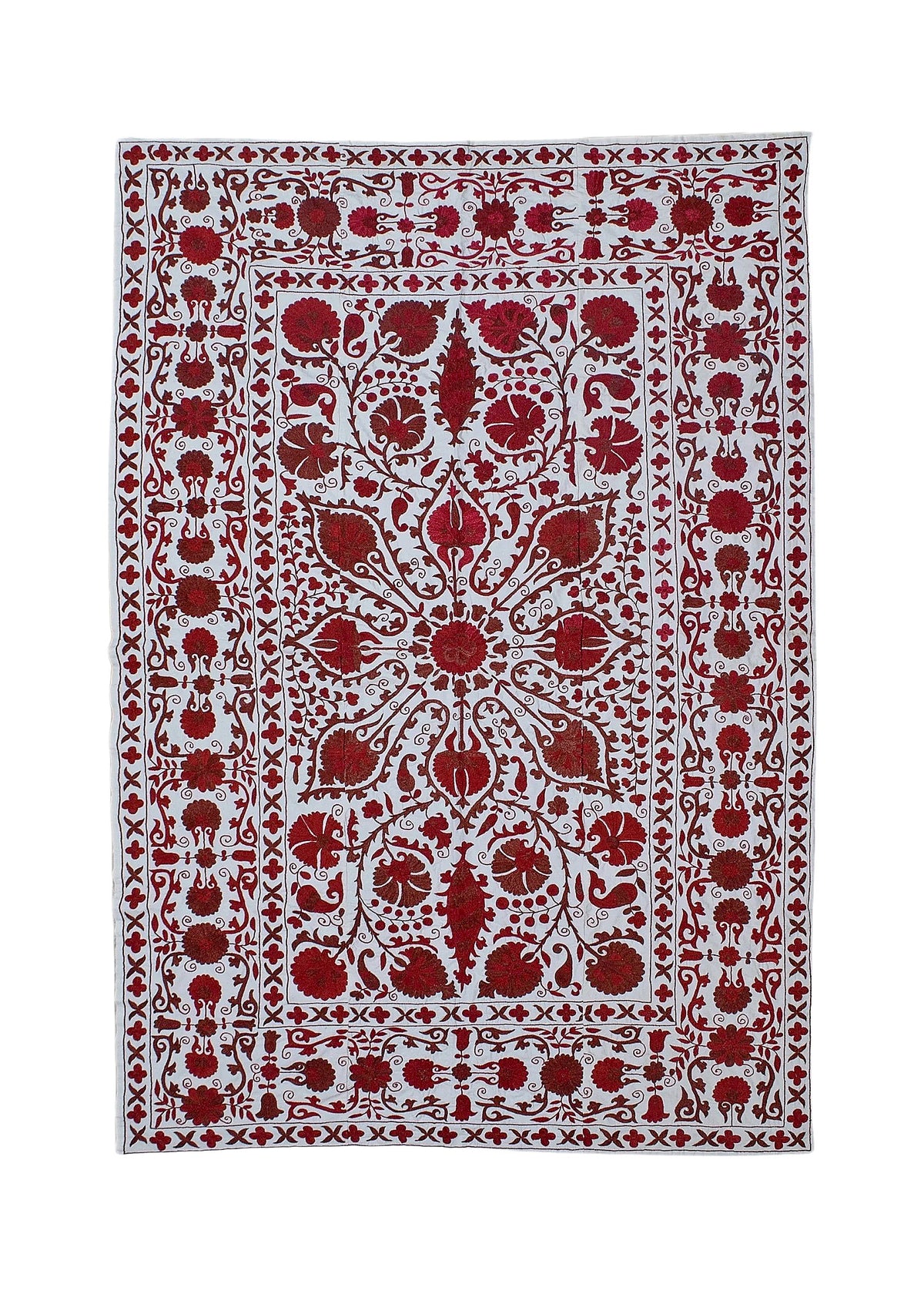 Hand-embroidered Uzbek cotton suzani featuring intricate red floral and pomegranate motifs on a white background.