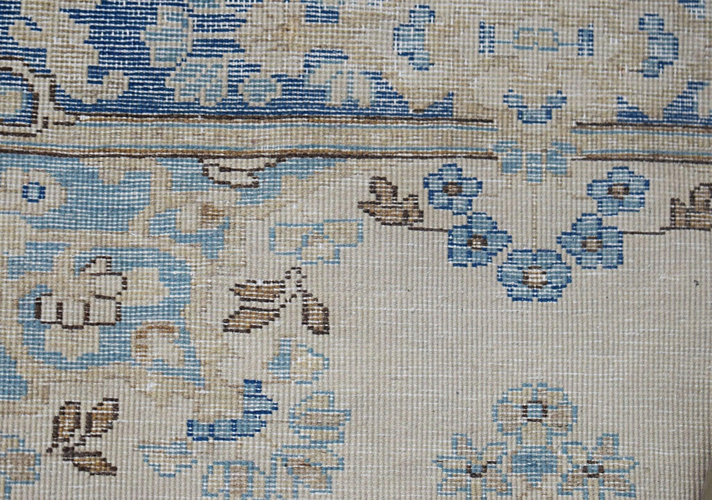 A vintage Persian Kerman runner featuring intricate blue and tan floral motifs on a neutral field.