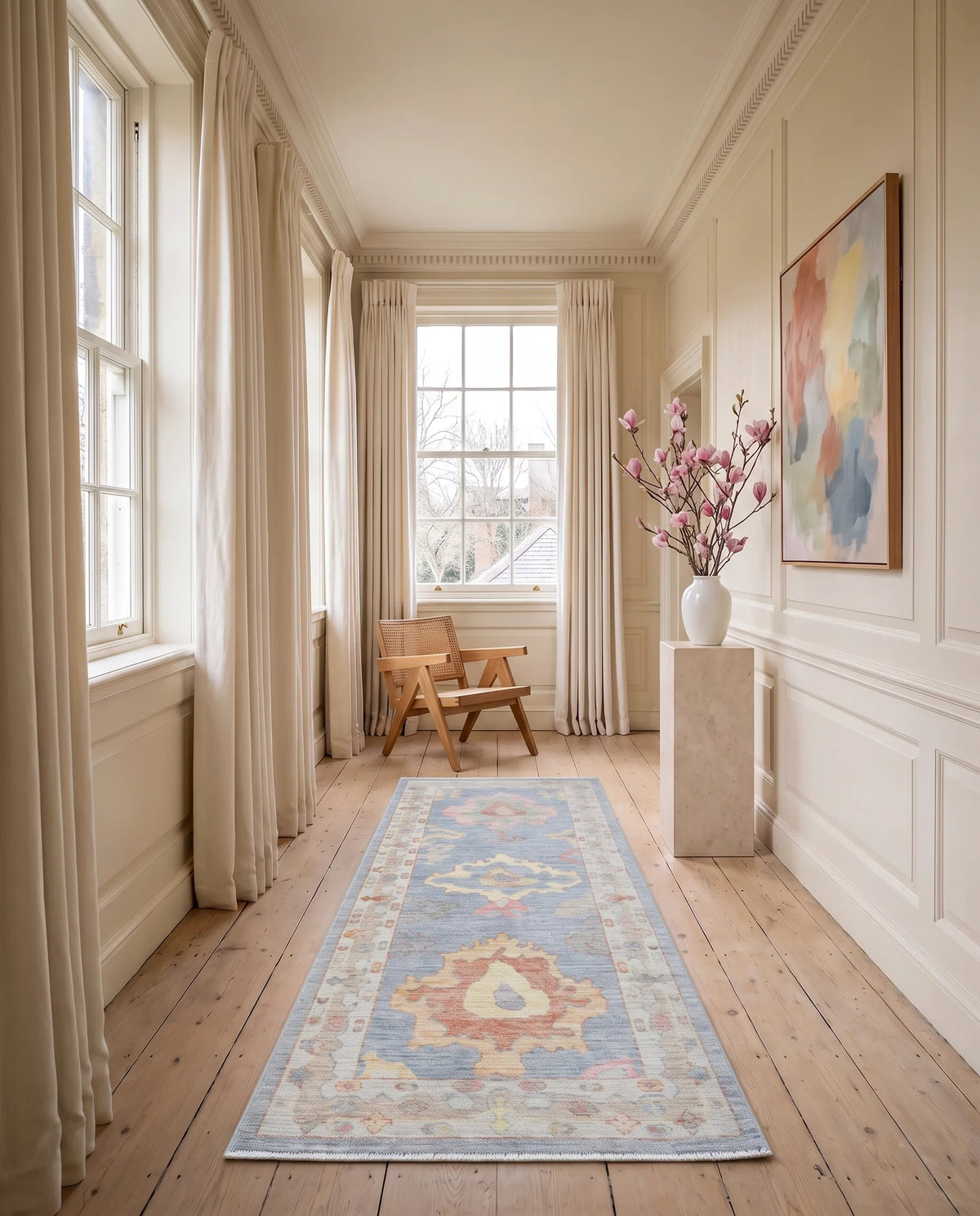 Hand-knotted wool Oushak runner with a soft blue, pink, and cream geometric pattern styled in a sunlit hallway.