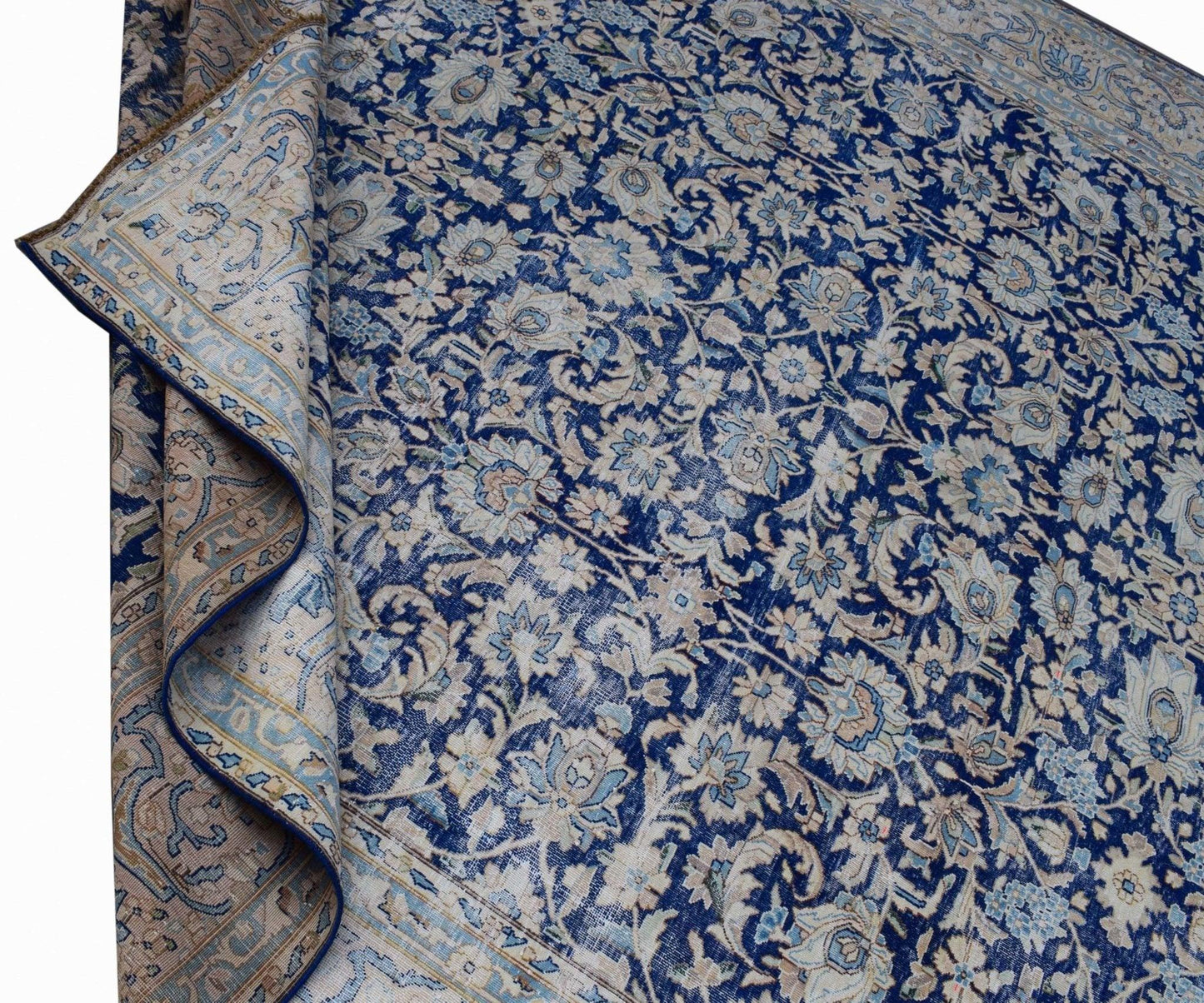 A vintage Persian Kerman rug featuring an intricate blue and cream floral pattern.