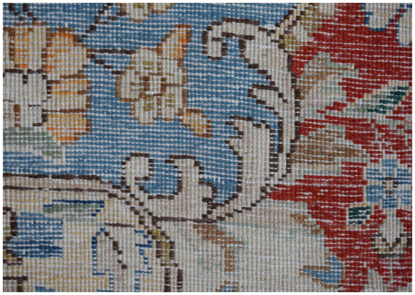 A close-up of a vintage Persian Kerman rug featuring intricate floral patterns in blue and red.
