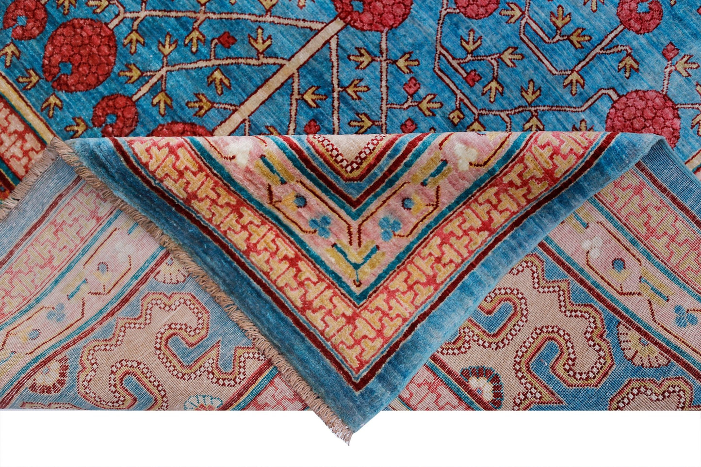 A handwoven Afghan Balkh rug featuring a blue field with red floral motifs and a folded corner.