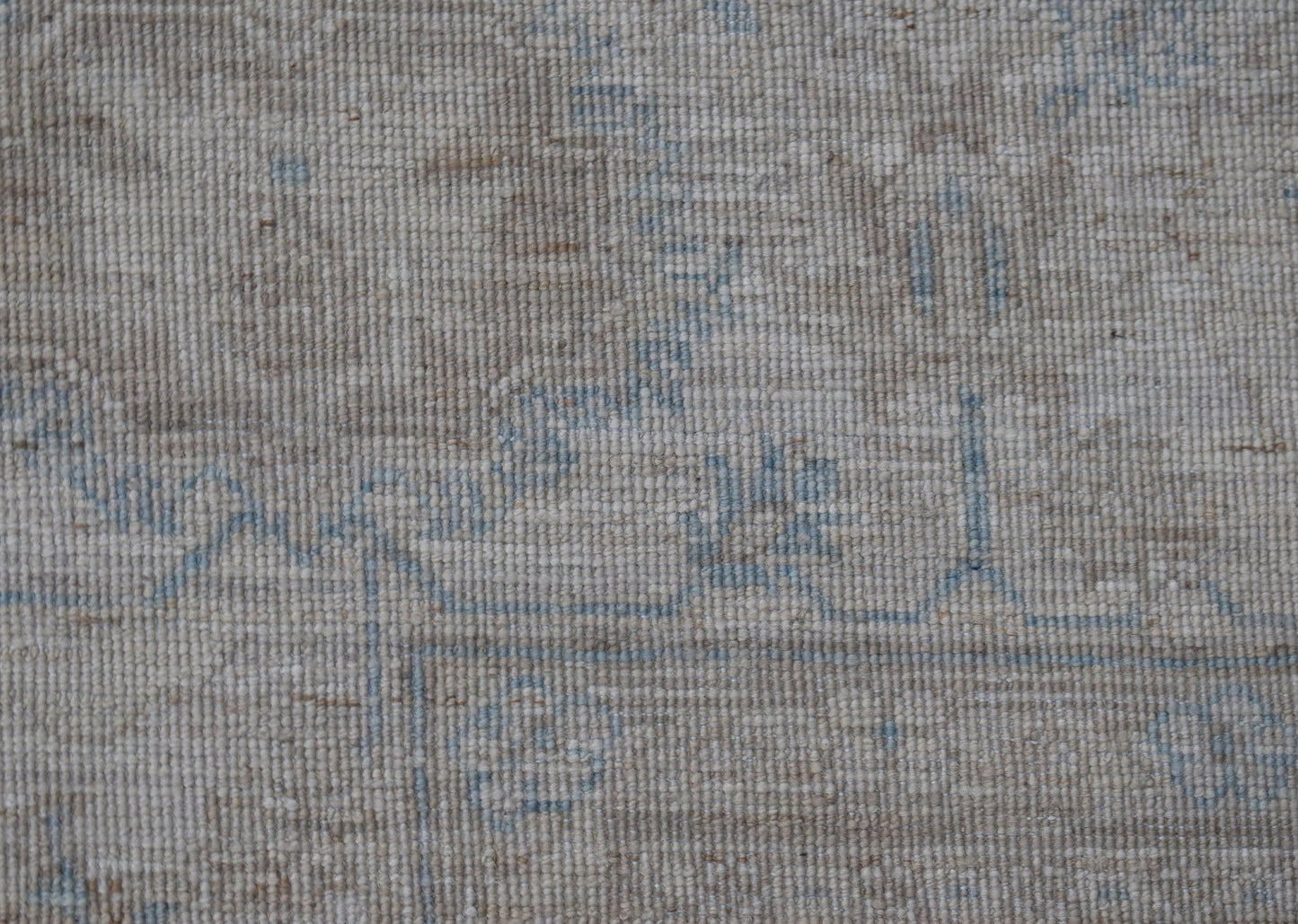 A close-up view of a handwoven Afghan Balkh rug featuring a neutral beige pattern with blue accents.