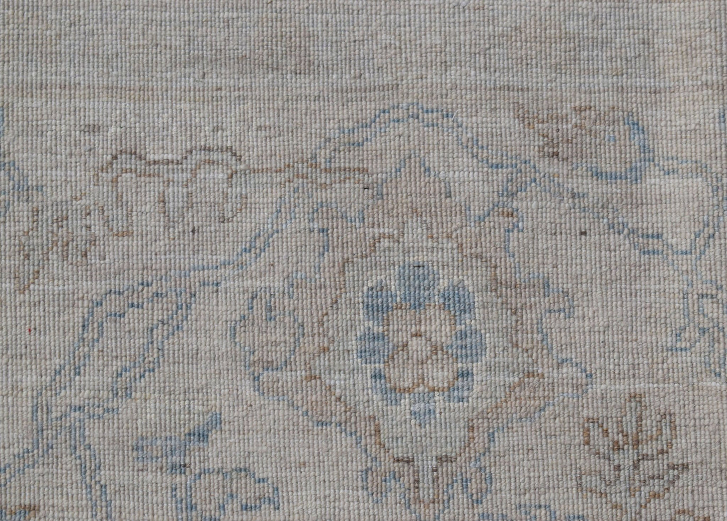 A handwoven Afghan Balkh rug featuring a traditional floral pattern in soft blue and beige tones.