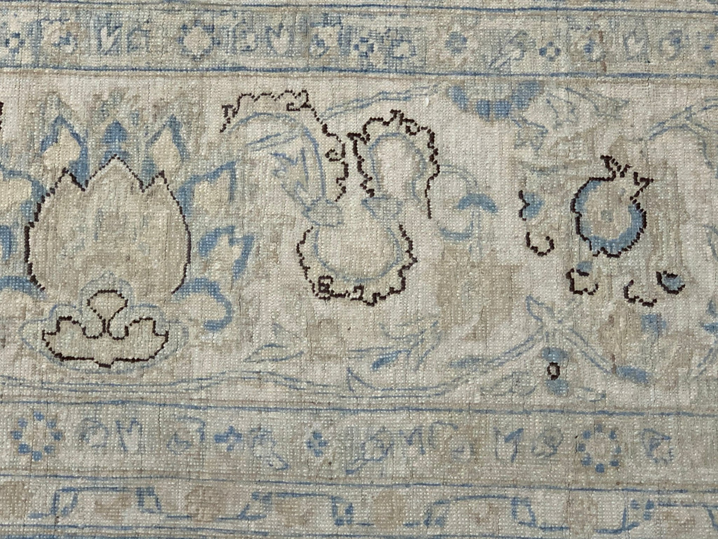 A close-up of an Afghan Balkh rug featuring intricate floral patterns in blue and beige tones.