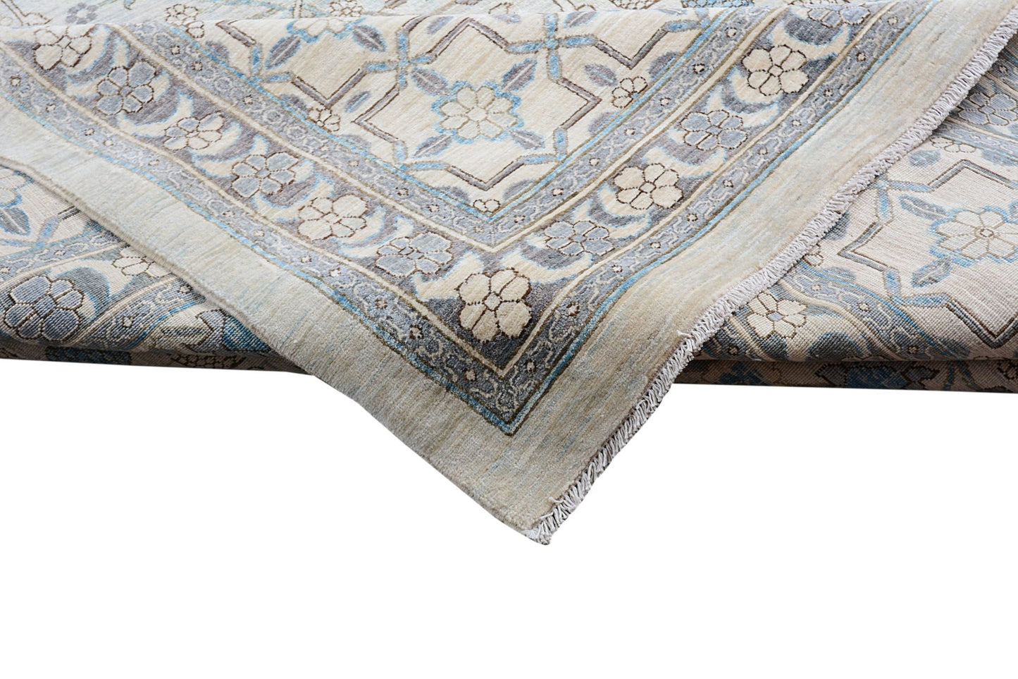 A folded Afghan Balkh rug featuring a traditional floral pattern in soft blue and beige tones.