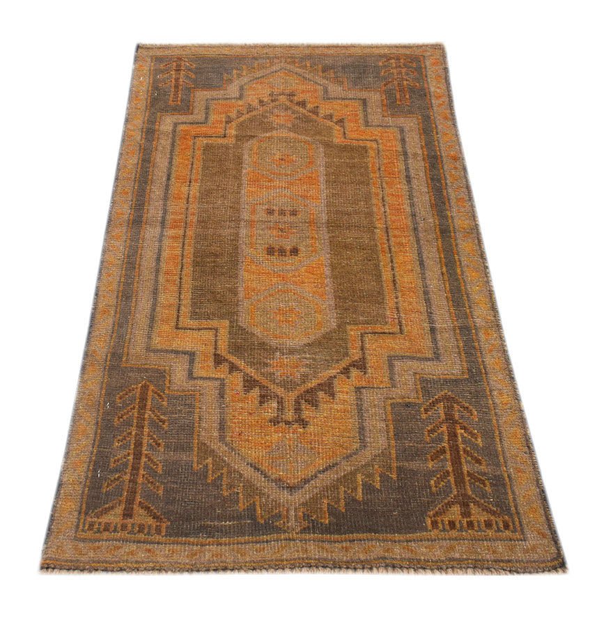 A handmade Afghan Baluch rug featuring a geometric medallion pattern in shades of brown and orange.