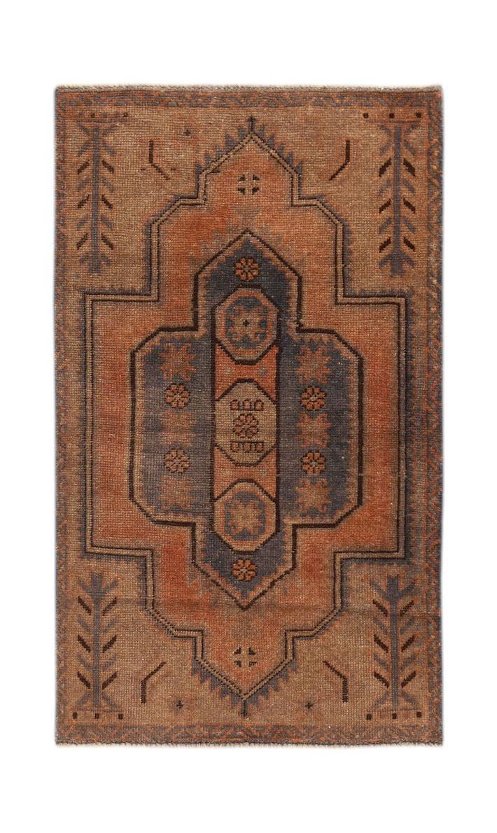 Handmade Afghan Baluch rug featuring a geometric medallion pattern in rust and charcoal tones.