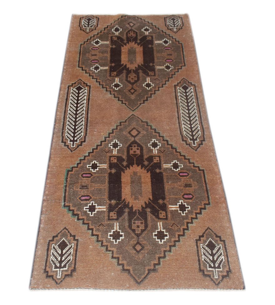 Handmade Afghan Baluch runner rug featuring two dark brown geometric medallions on a tan field.