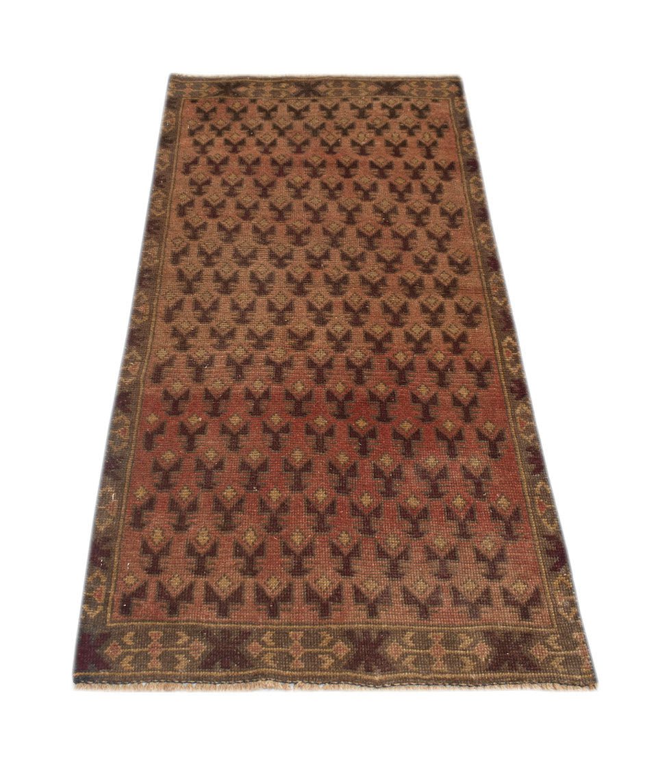 A handmade Afghan Baluch rug featuring a repeating geometric pattern in shades of red and brown.