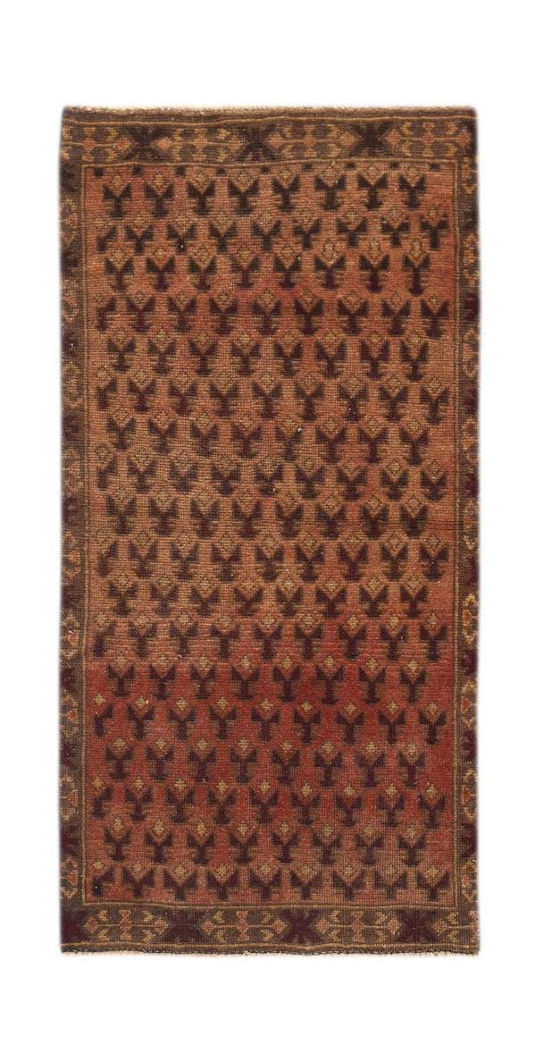 A handmade Afghan Baluch rug featuring a repeating dark geometric pattern on a rust-colored field.