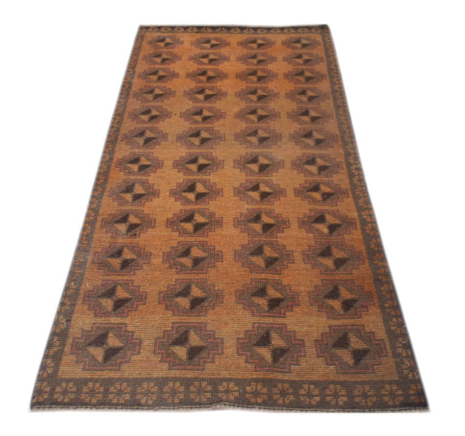 A handmade Afghan Baluch rug featuring a repeating geometric diamond pattern in brown and orange.