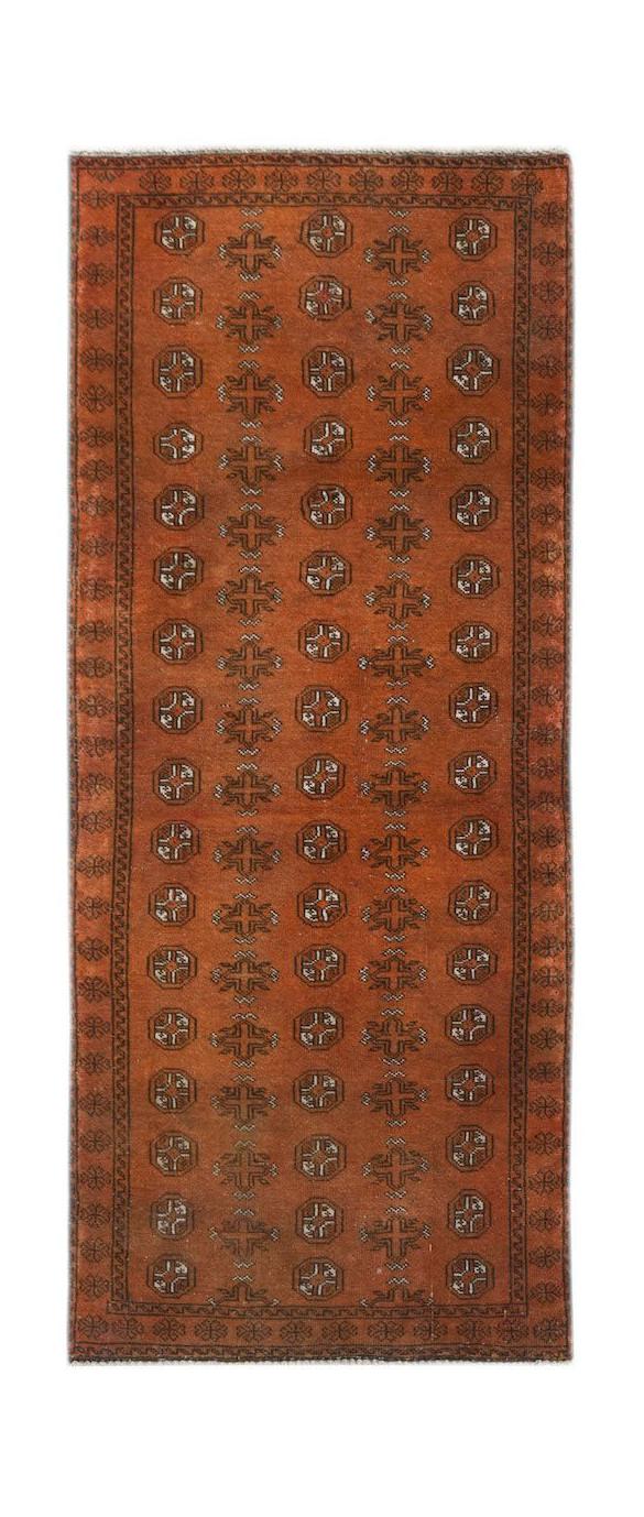 Handmade Afghan Baluch runner rug featuring a repeating geometric pattern on a rust-orange field.