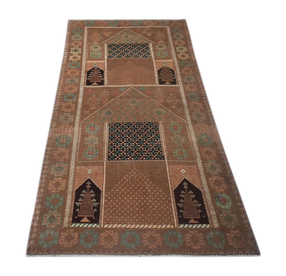 A handmade Afghan Baluch rug featuring geometric patterns and tree motifs in shades of brown.