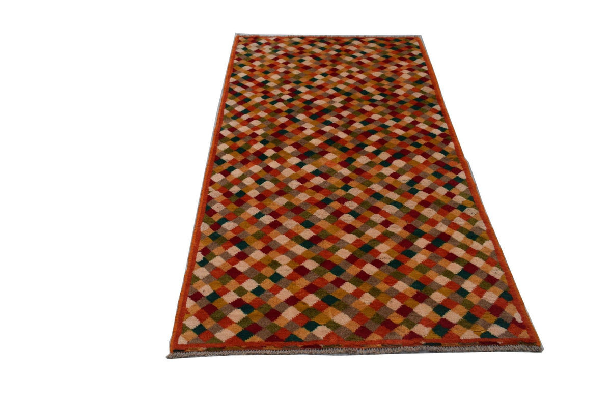 A handmade Afghan Baluch rug featuring a colorful diamond pattern in shades of red, brown, and ivory.