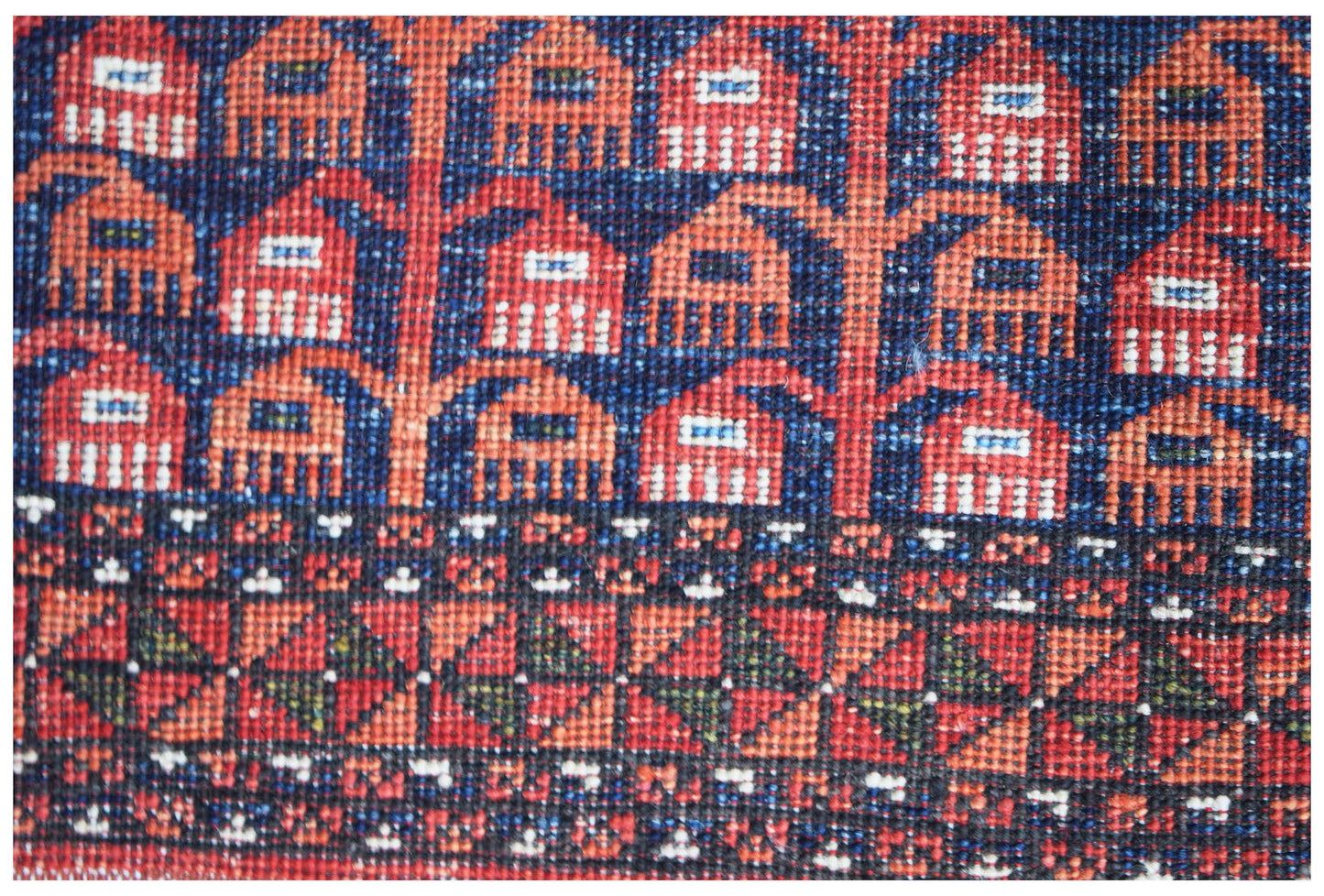 A close-up of an Afghan Chobi rug featuring intricate geometric patterns in red, blue, and ivory.