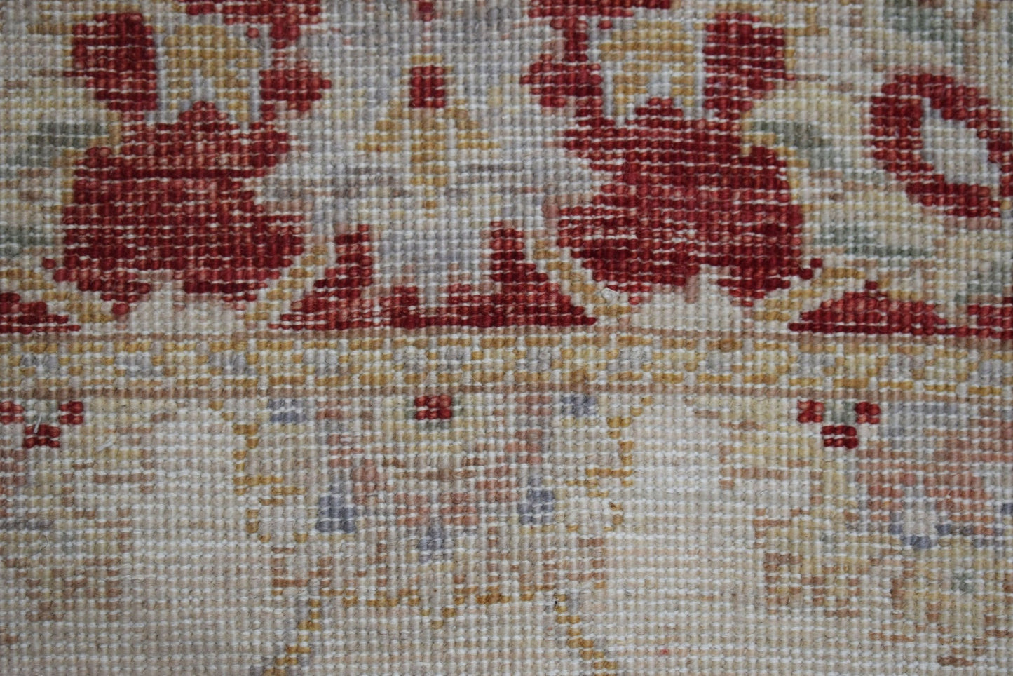 A close-up of a handwoven Afghan Chobi rug featuring traditional floral patterns in red and beige.