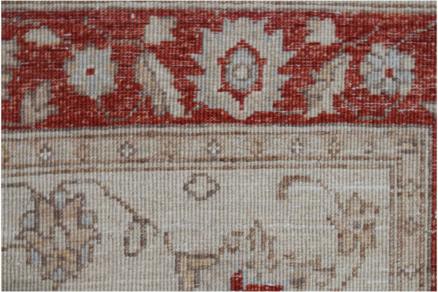 A close-up of a handmade Afghan Chobi rug featuring a red floral border and a beige field.
