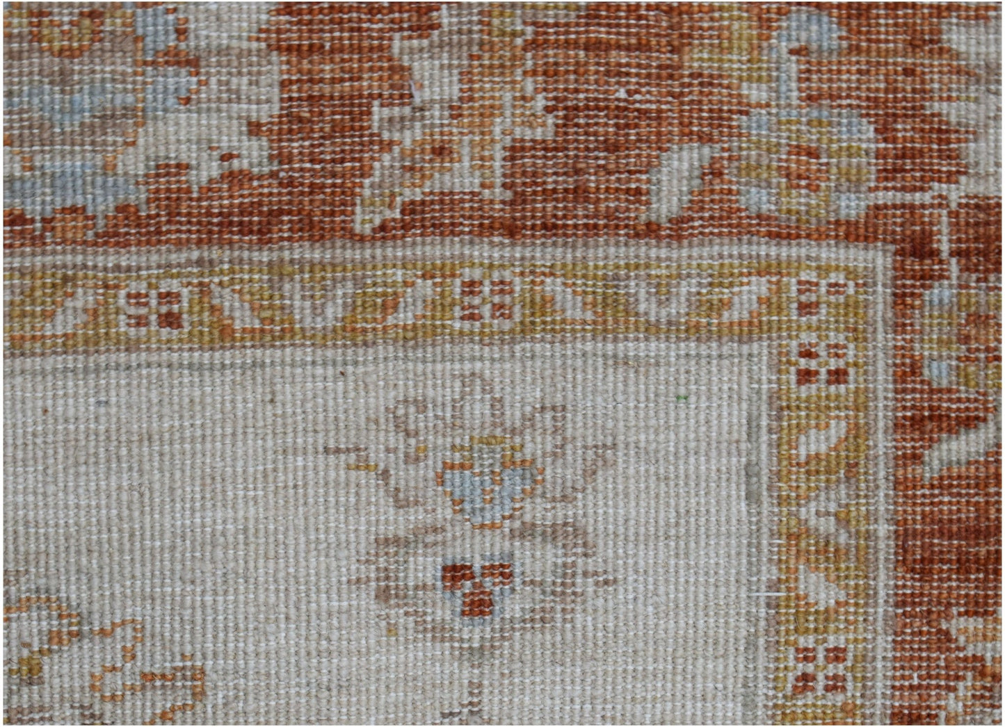 A close-up of an Afghan Chobi rug featuring a cream field with rust and gold floral patterns.