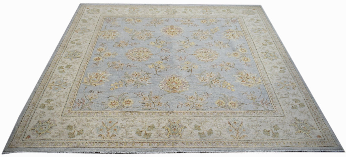 A rectangular Afghan Chobi rug featuring a light blue field with floral patterns and a beige border.