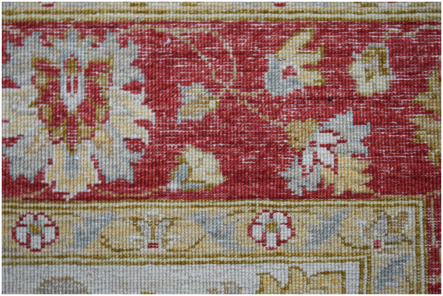 A close-up of a handwoven Afghan Chobi rug featuring traditional floral patterns in red and beige.