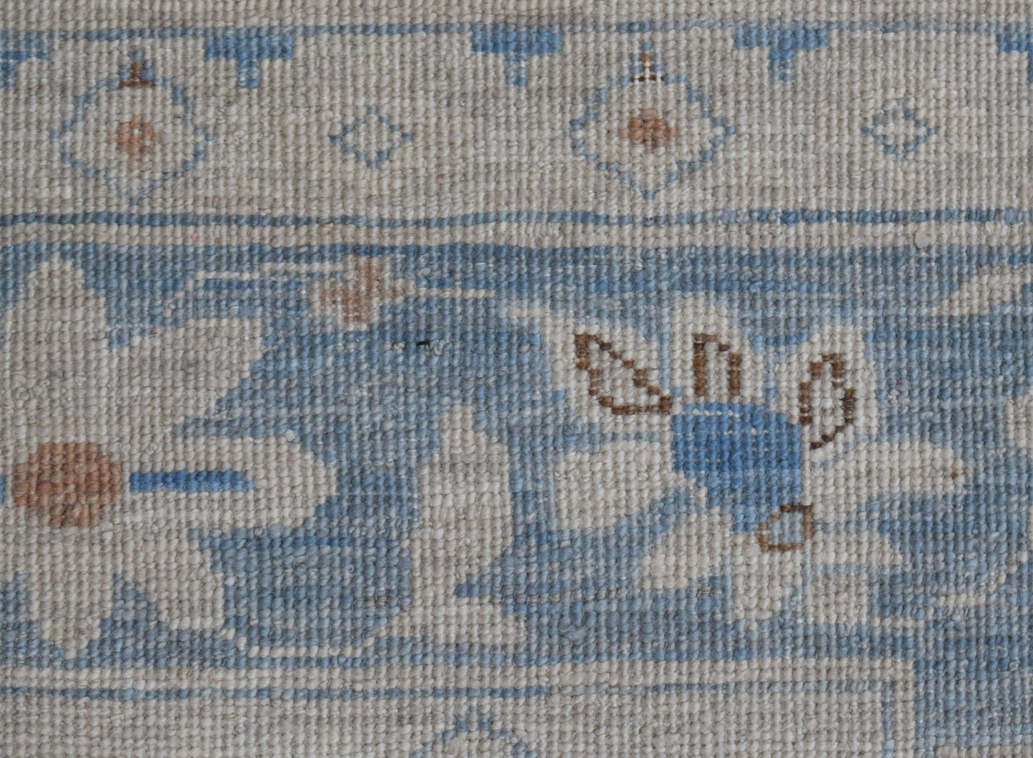 A close-up of a handwoven Afghan Chobi rug featuring traditional floral patterns in blue and beige.