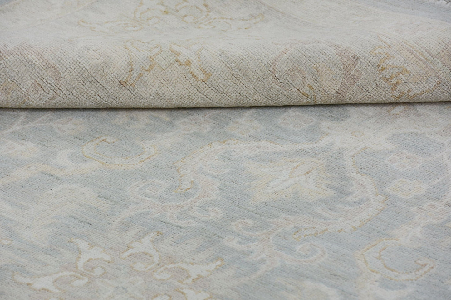 A handmade Afghan Chobi rug featuring a traditional floral pattern in soft blue and beige tones.