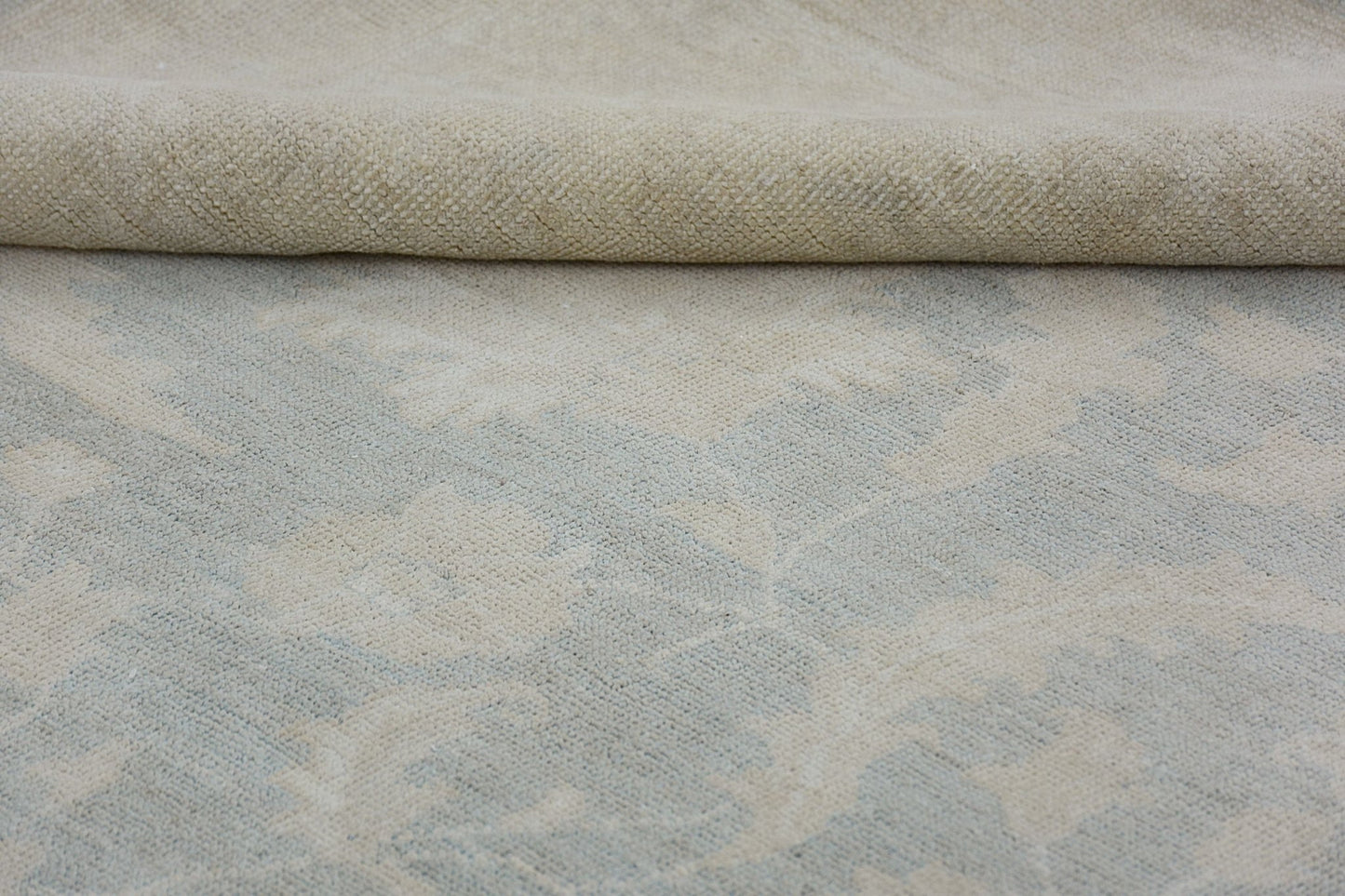 A close-up view of a handmade Afghan Chobi rug featuring a soft, neutral floral pattern.
