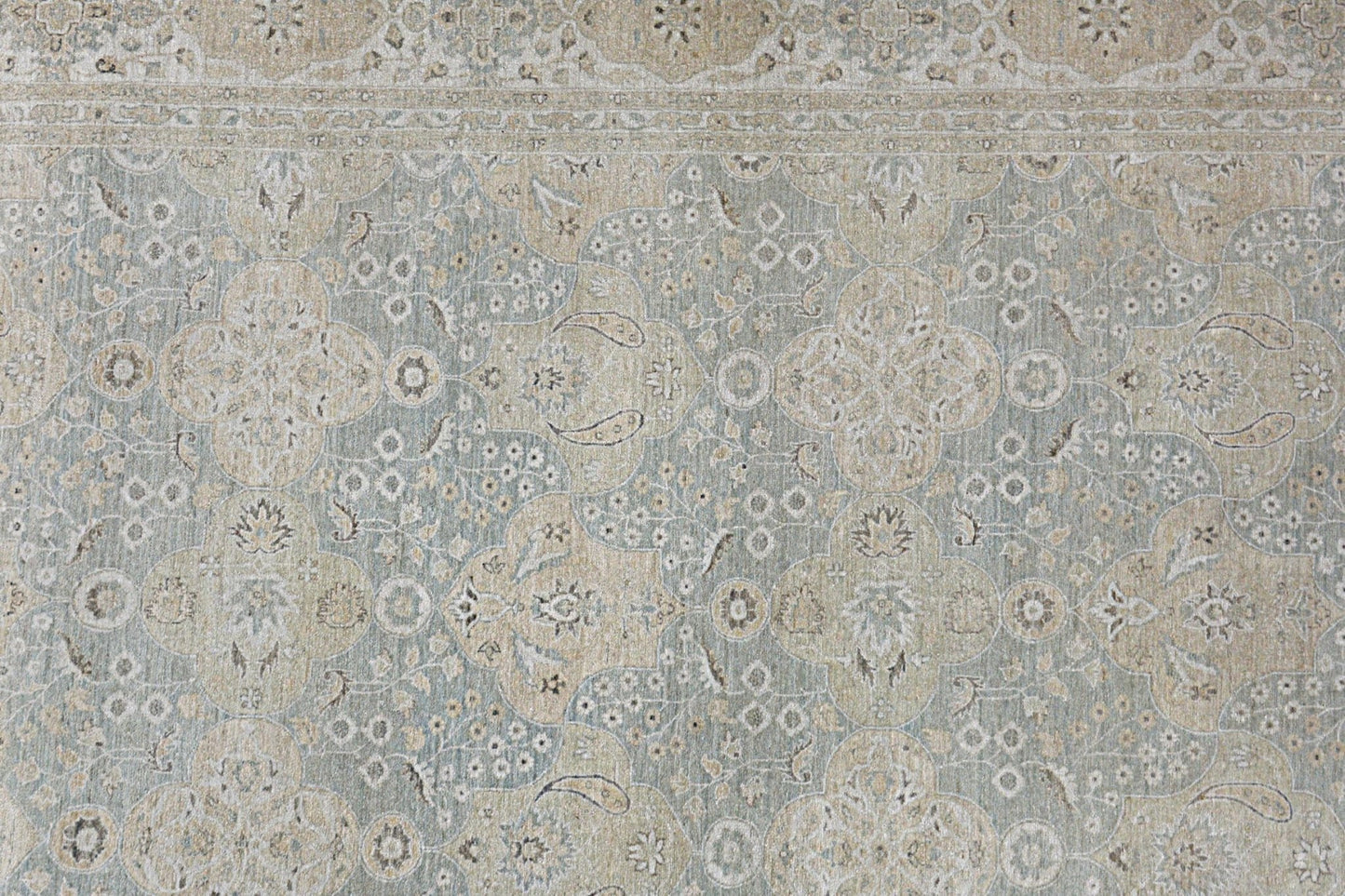 An Afghan Chobi rug featuring a traditional floral pattern in muted blue and beige tones.