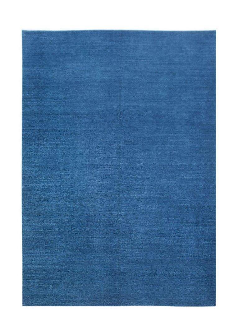 A rectangular, handwoven Afghan Chobi rug featuring a solid, deep blue wool texture.