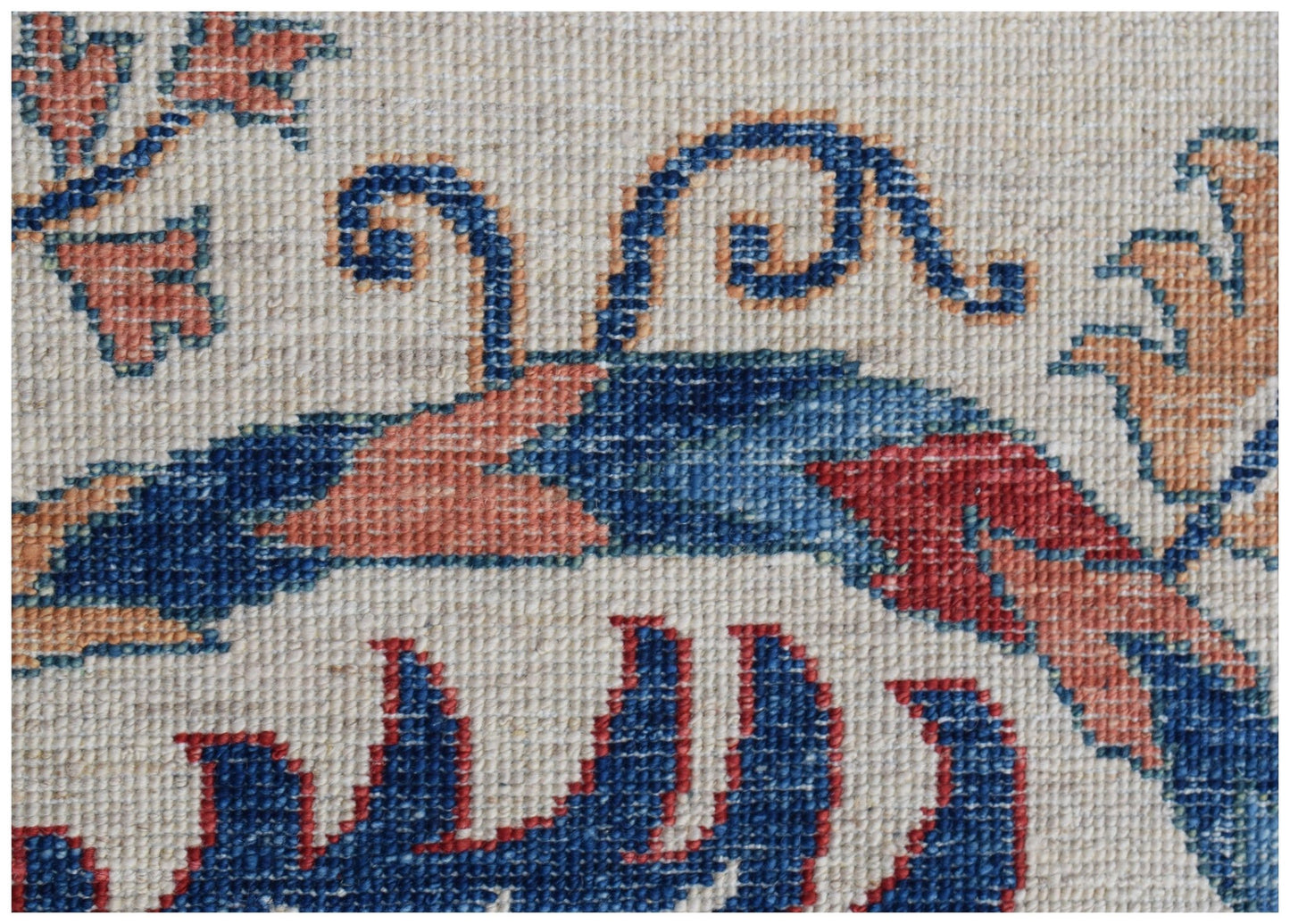 A close-up of a handwoven Afghan Chobi rug featuring intricate blue and red floral patterns.