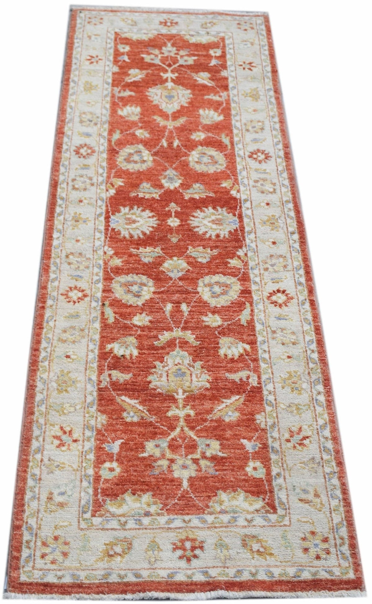 A handmade Afghan Chobi runner rug featuring a traditional floral pattern in red and cream tones.