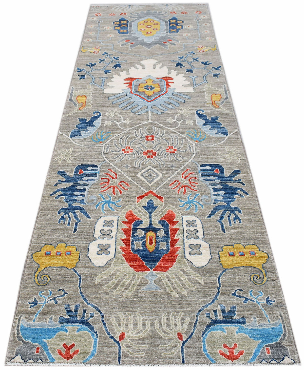Hand-knotted Afghan Chobi runner in grey wool with a vibrant, symmetrical floral pattern in blue, red, and yellow.