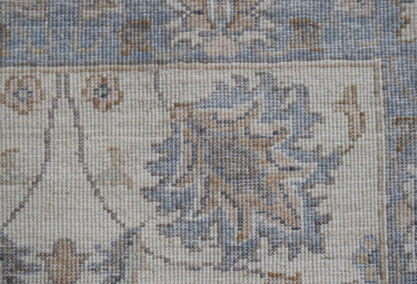 A close-up of an Afghan Chobi runner featuring intricate floral patterns in muted blue and tan tones.