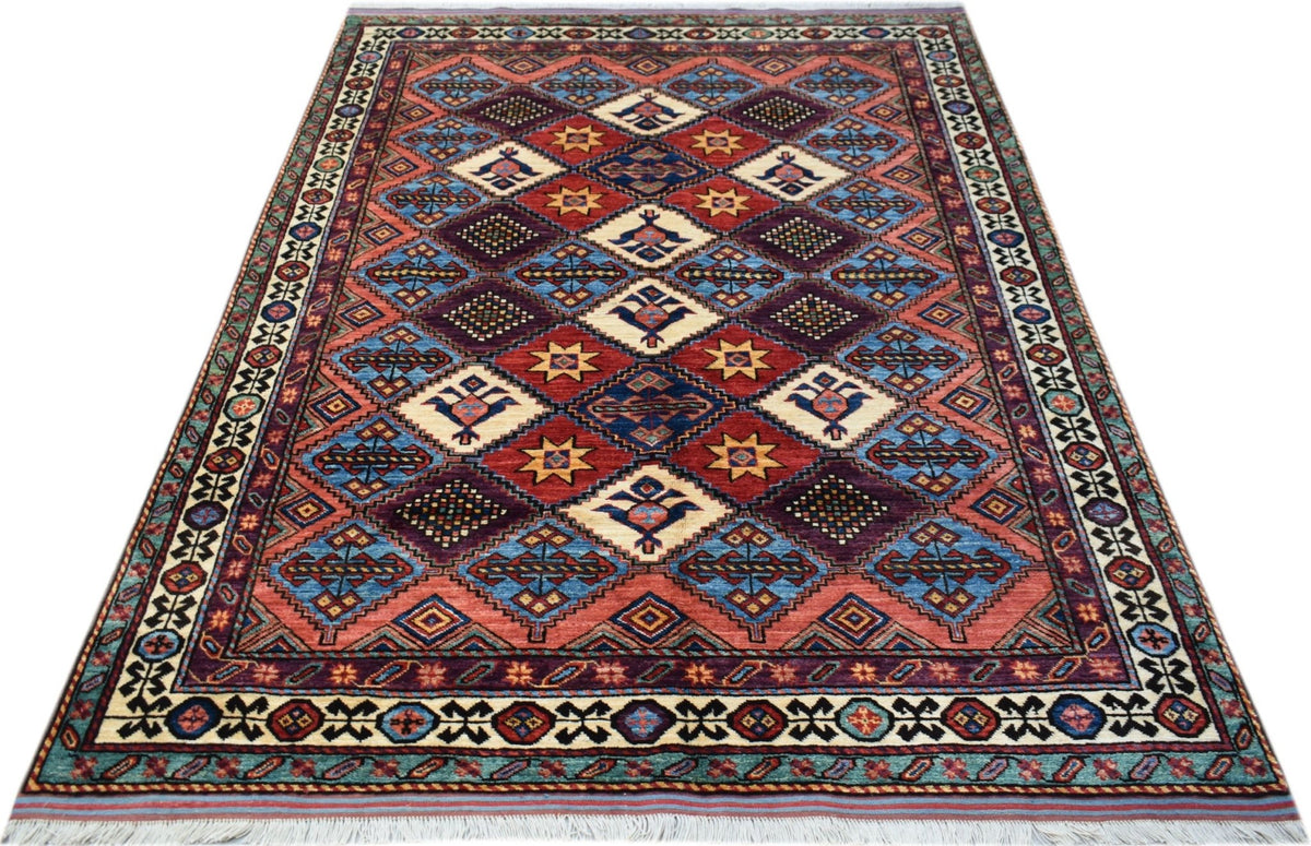 Hand-knotted Afghan Herati rug featuring a red, blue, and cream diamond lattice pattern with a white fringed edge.
