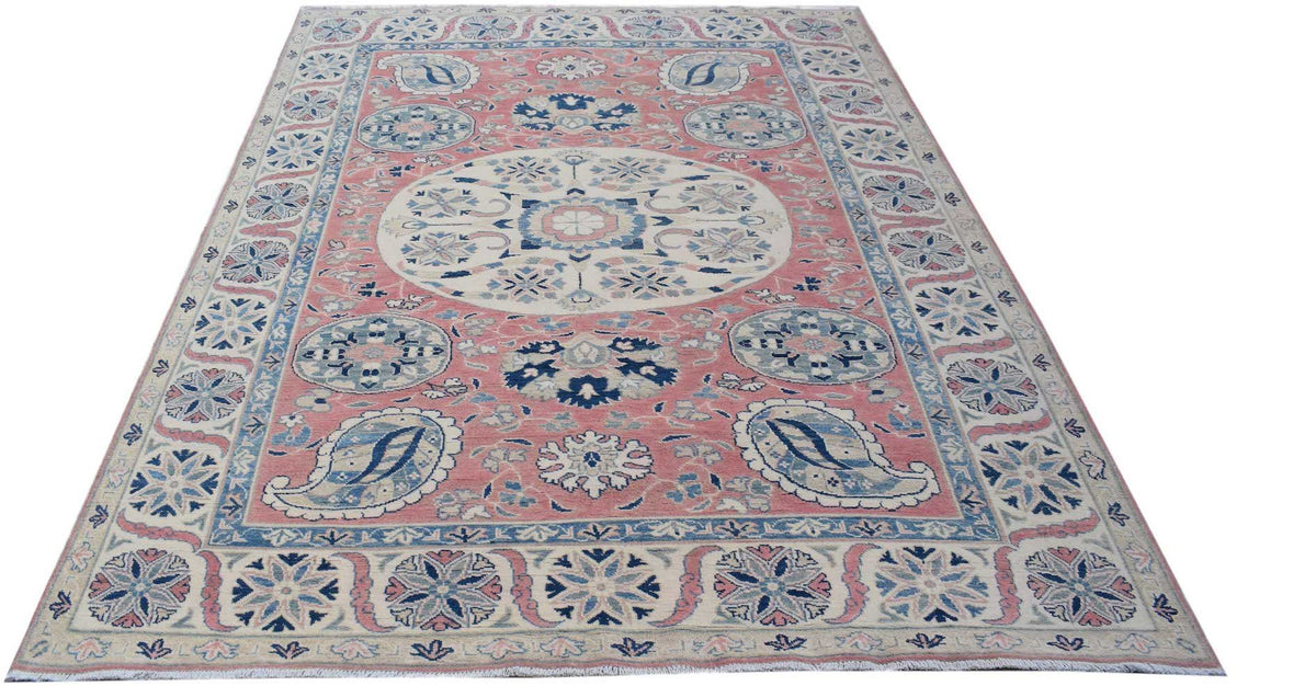 Handmade Afghan Kazakh rug featuring a pink field with blue and cream floral and paisley motifs.