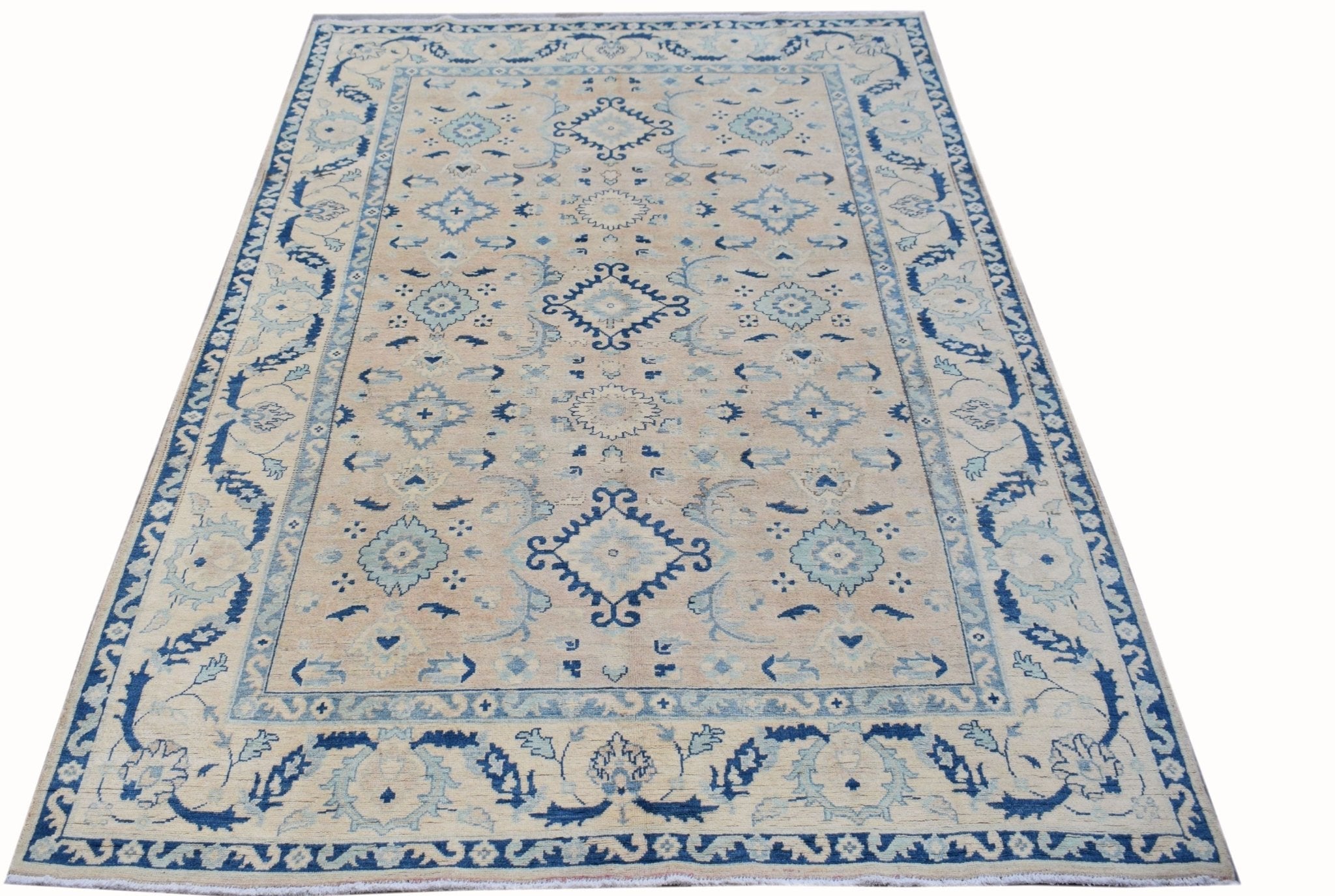 A handmade Afghan Kazakh rug featuring traditional blue geometric patterns on a beige wool field.