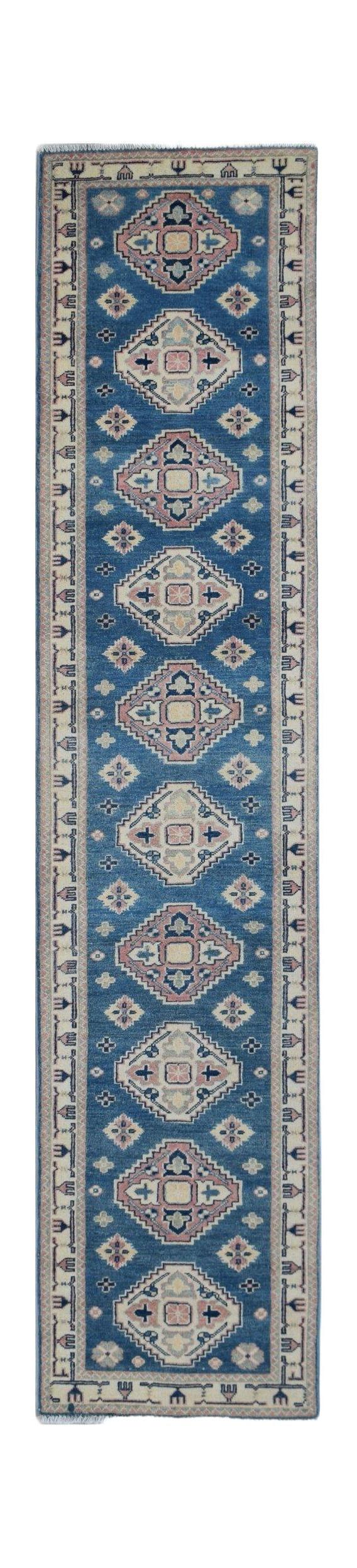 A handmade Afghan Kazakh runner rug featuring repeating geometric diamond motifs in blue and pink.