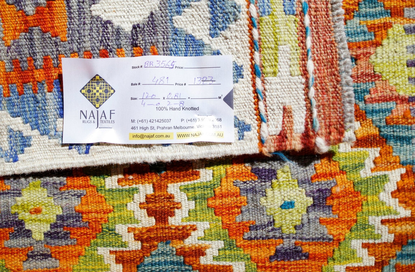 A handwoven Afghan Maimana Kilim featuring a vibrant geometric pattern in orange, green, and blue.