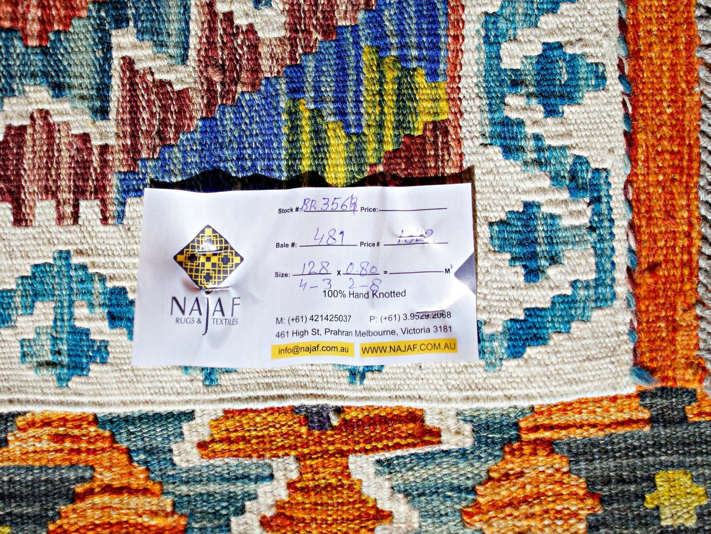 A handmade Afghan Maimana kilim rug featuring a vibrant geometric pattern in blue, orange, and red.