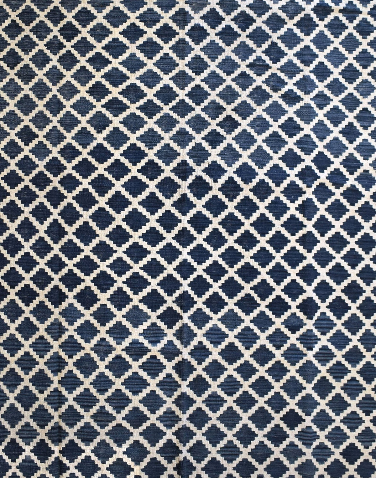 Handmade Afghan Maimana kilim rug featuring a repeating dark blue and cream geometric pattern.