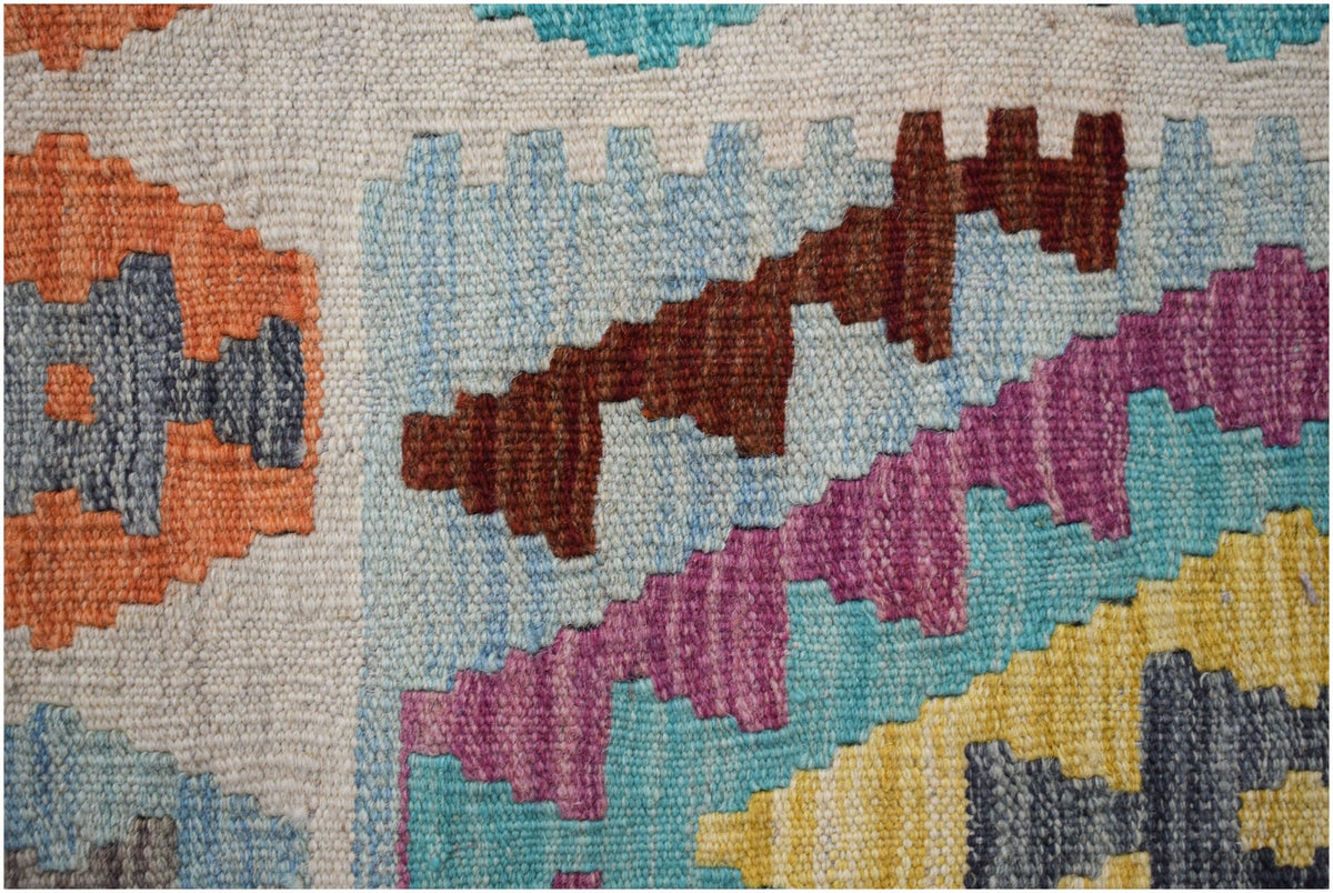 A close-up of a handmade Afghan Maimana kilim featuring geometric patterns in vibrant colors.